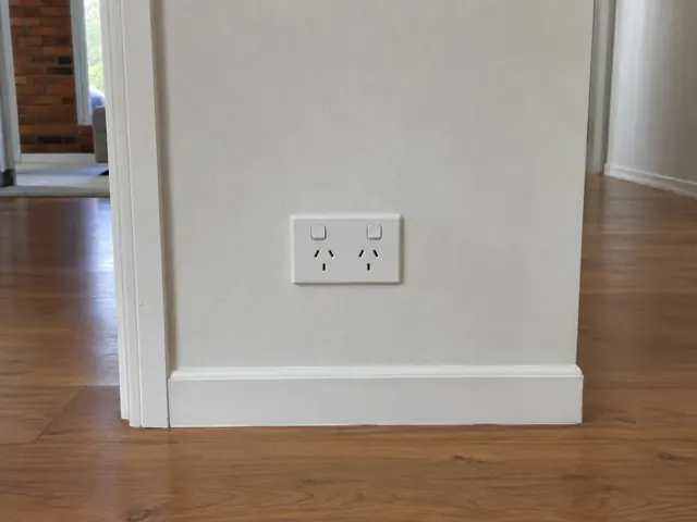 White double power point on a painted wall above timber floorboards in a home interior in Pimpama