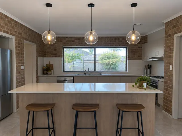 Three glass pendant lights over a kitchen island in a tiled home kitchen in Coomera